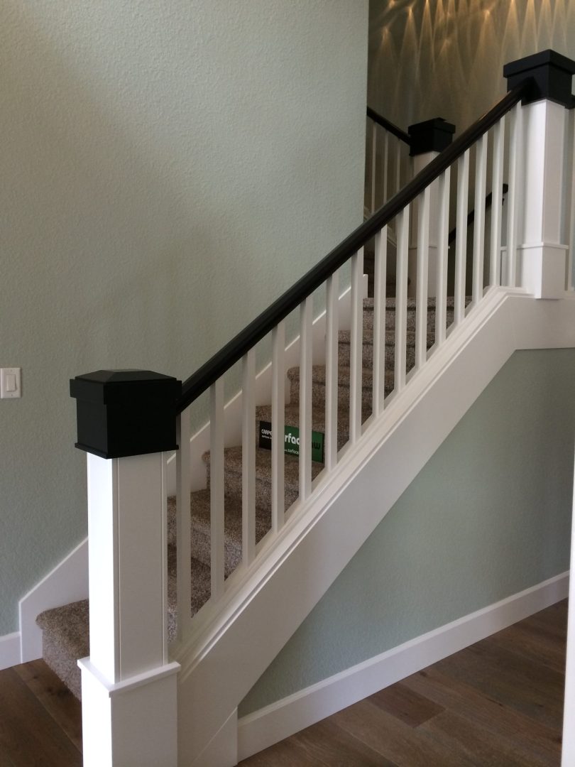 Carpeted stairs with black stair rail and white balusters